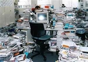 Un bureau encombré par tout un tas de piles de documents inutiles